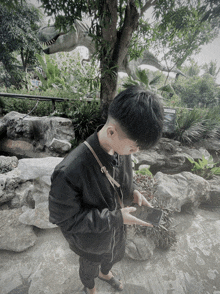 a young man in a black jacket is looking at a cell phone