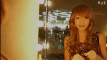 a woman in a wig looks at herself in a mirror with the letter q on the bottom right
