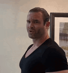a man in a black shirt is making a funny face in front of a framed picture