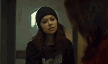 a woman wearing a beanie is looking at herself in the mirror .
