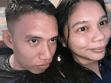 a man and a woman are posing for a picture and the woman is wearing earrings