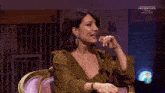 a woman laughs while sitting in front of a screen that says " las gentiles "