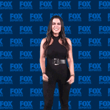 a woman is standing in front of a fox deportes wall
