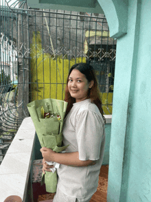 a woman holds a bouquet of flowers in front of a fence