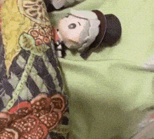 a stuffed doll with a top hat is laying on a bed with a blanket .