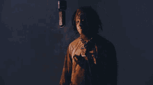 a man with dreadlocks stands in front of a microphone with a chain around his neck