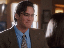 a man wearing glasses and a suit is smiling at a woman