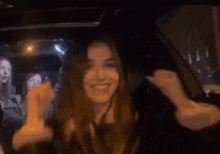 a woman is sitting in the back seat of a car with her hands in the air .