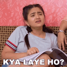 a woman sitting on a couch reading a book with the words kya laye ho written on the bottom