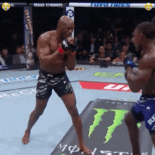 two men are fighting in front of a monster energy drink