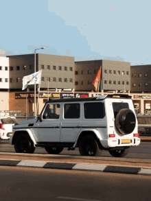 a white suv is driving down a street in front of a building with a sign that says ' ' ' '