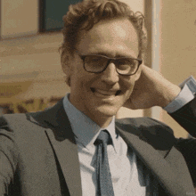 a man in a suit and tie is smiling and holding his hand to his ear