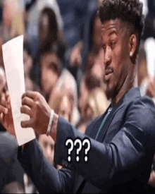 a man in a suit holds a piece of paper in his hand and says " question "