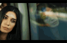 a woman is standing in front of a window with her reflection in the window .
