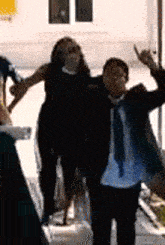 a man and a woman are standing next to each other with their arms outstretched .