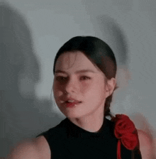 a close up of a woman wearing a black top with a red flower in her hair .
