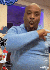 a man in a blue shirt is making a funny face and pointing