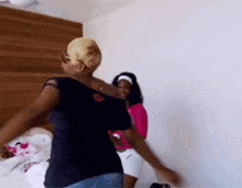 two women are standing next to each other in a bedroom .