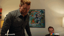 a man standing in front of a painting with nbc written on the bottom right