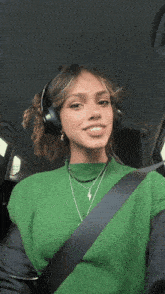 a woman wearing headphones and a green sweater is in a car