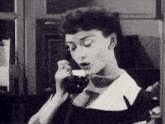a woman in a black and white photo is talking on a phone