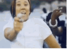 a woman in a white shirt is singing into a microphone while another woman looks on .