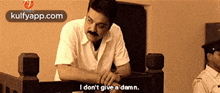 a man with a mustache is sitting in a chair and saying i don 't give a damn