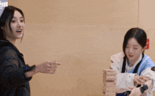 two women are playing a game with a stack of wooden blocks that says jenga on it
