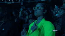a woman in a neon green jacket is giving a thumbs up at a bet event