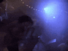 a person is dancing in a dark room with blue lights