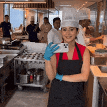 a woman in a chef 's hat is taking a picture of herself in a kitchen
