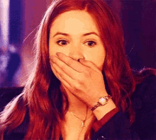 a woman is covering her mouth with her hand and wearing a watch