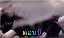 a blurred image of a roller coaster with the words " ตอน นี้ " in the bottom right corner