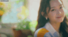 a close up of a woman 's face with a blurry background and the sun shining on her face .