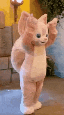 a stuffed animal in a pink and white fox costume is standing on its hind legs .