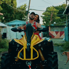 a man and woman are riding a yellow can-am vehicle