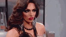 a close up of a drag queen holding a glass of water .