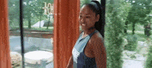 a woman in a tank top is standing in front of a window .