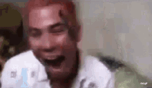 a close up of a man laughing with his eyes closed .