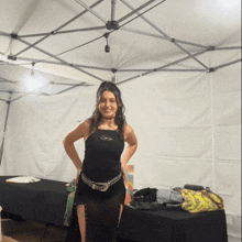 a woman in a black dress is standing in front of a tent