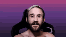 a shirtless man with a beard is sitting in a chair with a purple background