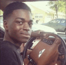a man is sitting in the driver 's seat of a bentley car and making a funny face .