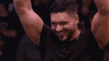 a man in a black shirt is smiling with his arms in the air .