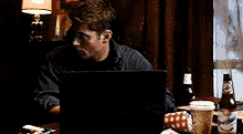 a man is sitting at a table using a laptop computer .