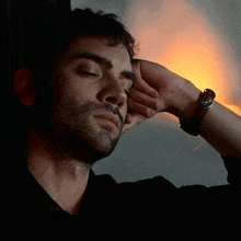 a man with his eyes closed is wearing a wristwatch