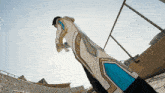 a person in a long white and blue costume is standing on a ledge