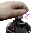 a hand is holding a robot with hearts on it 's chest .
