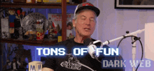 a man is sitting in front of a microphone with the words tons of fun dark web behind him