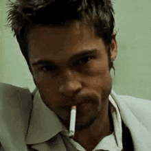 a man is smoking a cigarette in his mouth in a close up .
