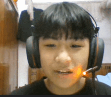 a young boy wearing headphones and a microphone is talking on a video call .